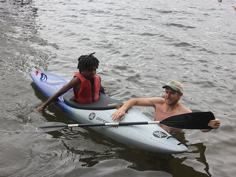 counselor helping camper in kayak