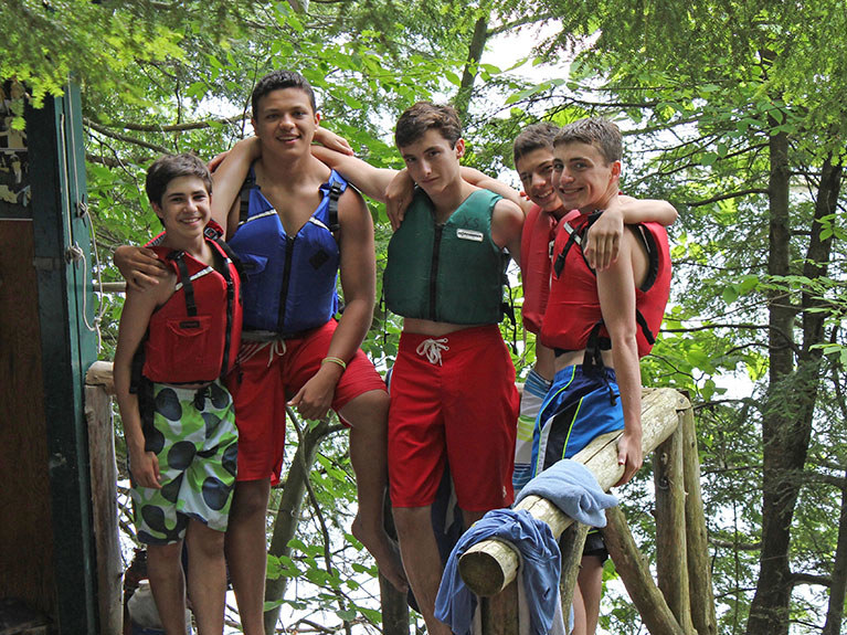 Group of boys in trees near lake in life jackets