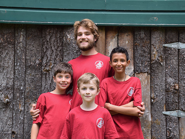 Counselor and three boys smiling