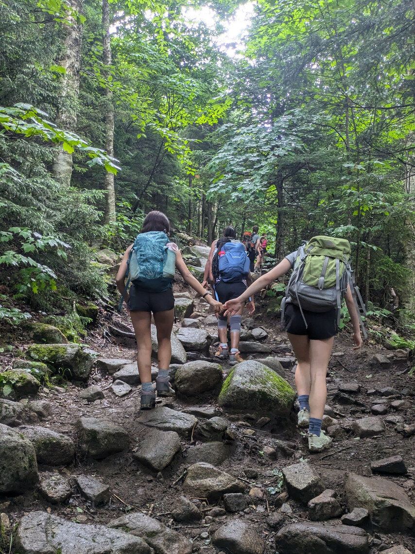 Campers holding hands while hiking up a mountain trail
