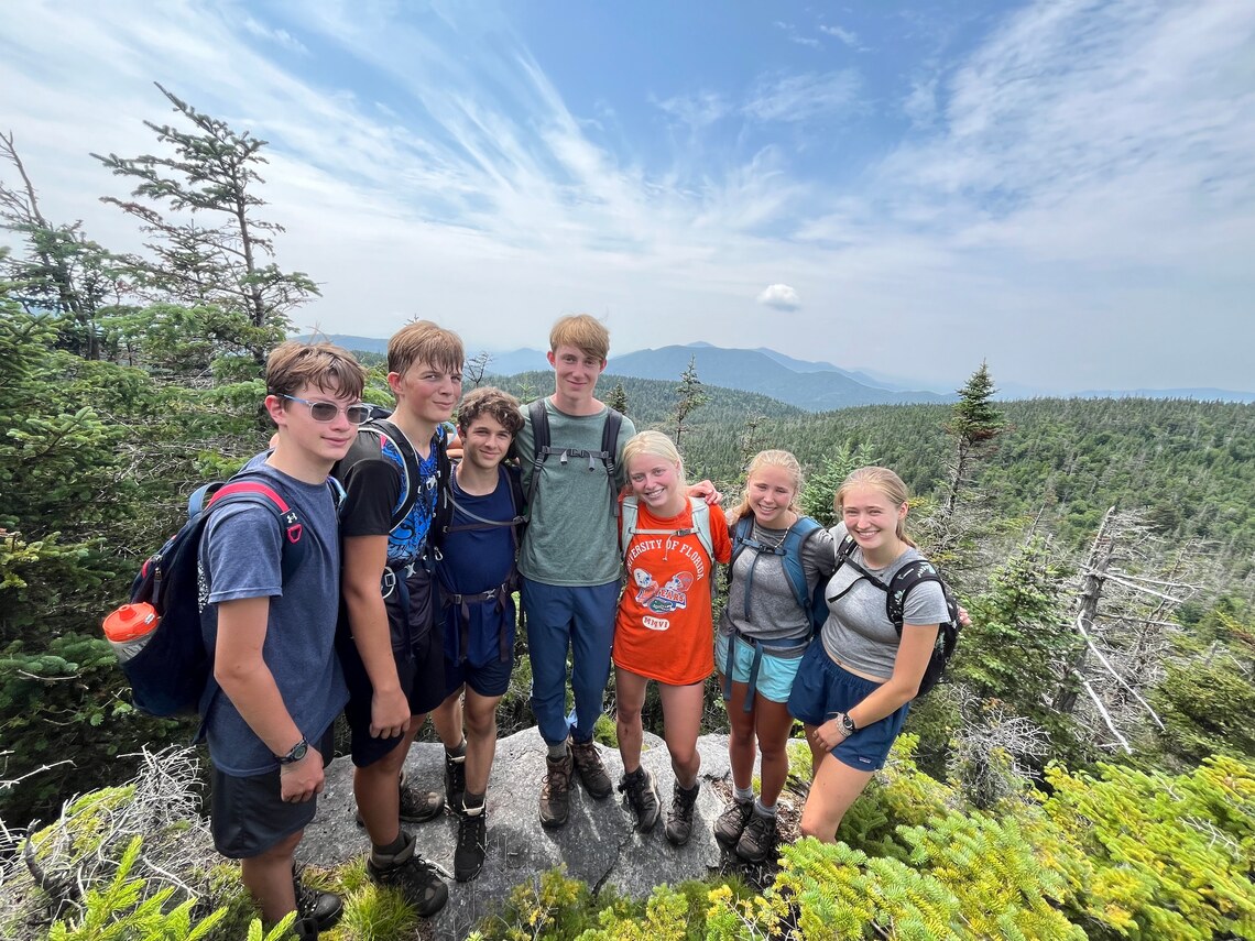 A group of campers smiling on top of a mountain